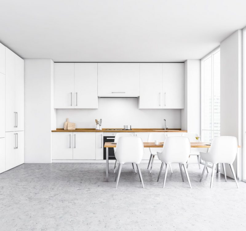 Interior of modern minimalist kitchen with white walls, concrete floor and white cupboards with built in sink and oven. Dining table with charis. 3d rendering
